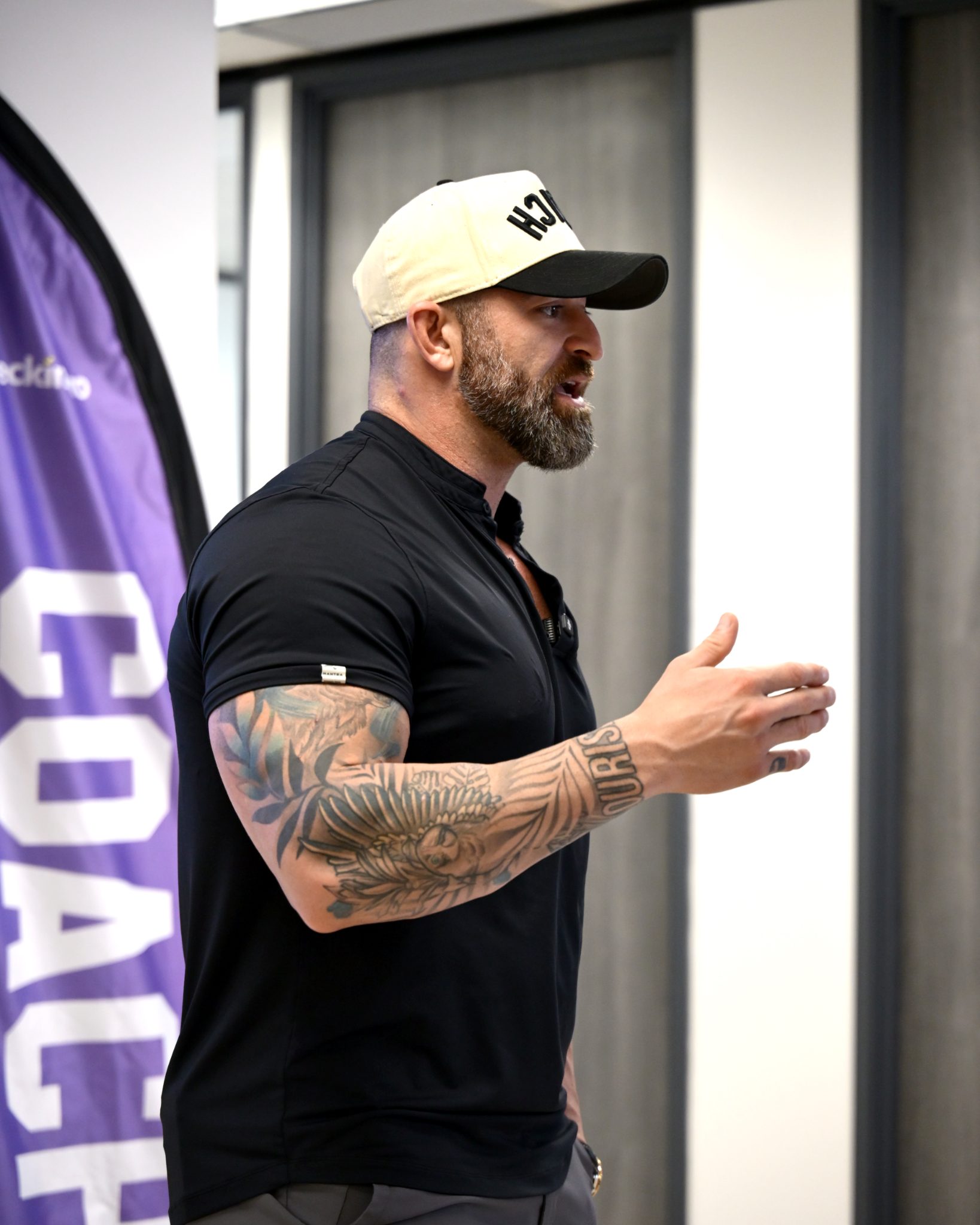 A coach in a COACH cap speaking to the room beside a COACH banner