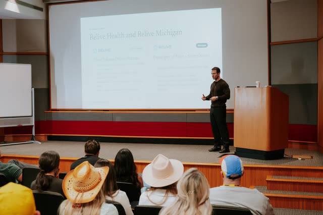 Wide view of the lecture hall as attendees in cowboy hats watch a talk