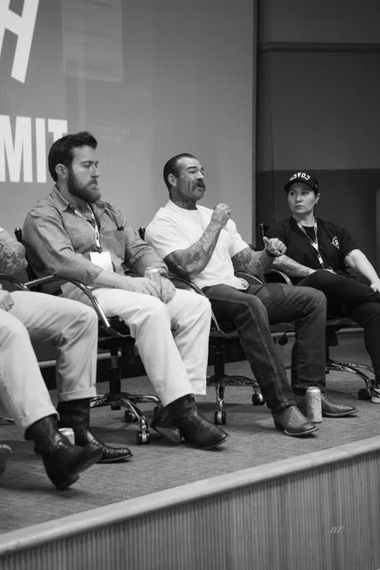 Black and white shot of panelists talking on stage