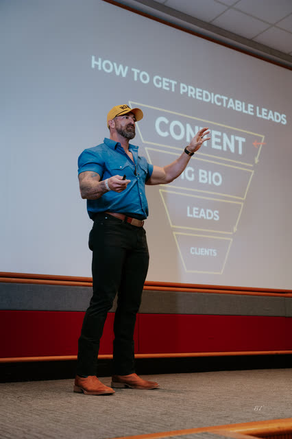 Mike Crowson in a yellow COACH cap walking the room through his leads funnel slide