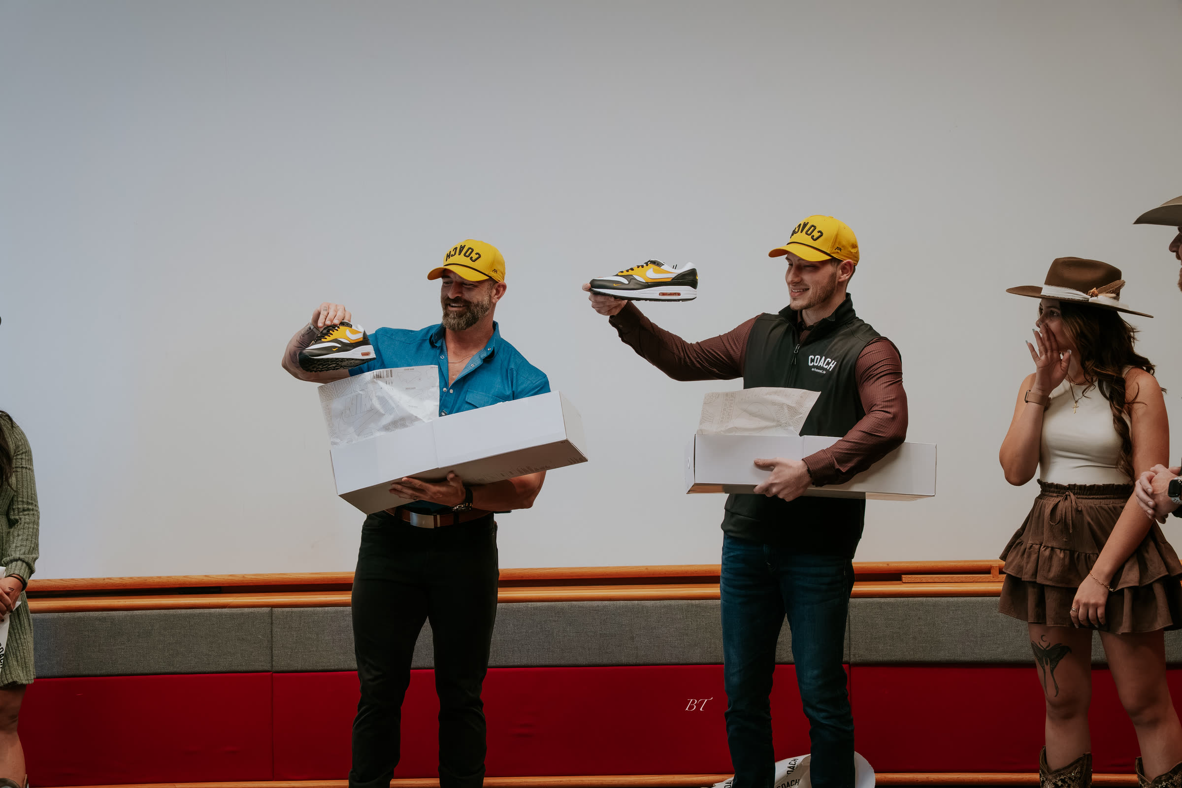 Mike and Bakker holding up sneakers from COACH boxes on stage