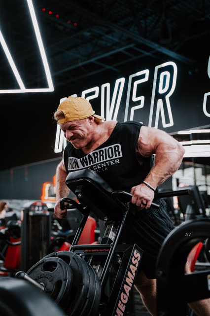 Coach in an Iron Warrior tank straining through a T-bar row