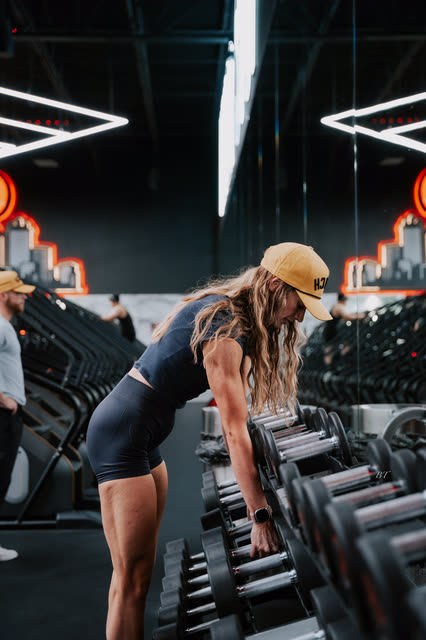 Coach in a COACH cap racking her dumbbells