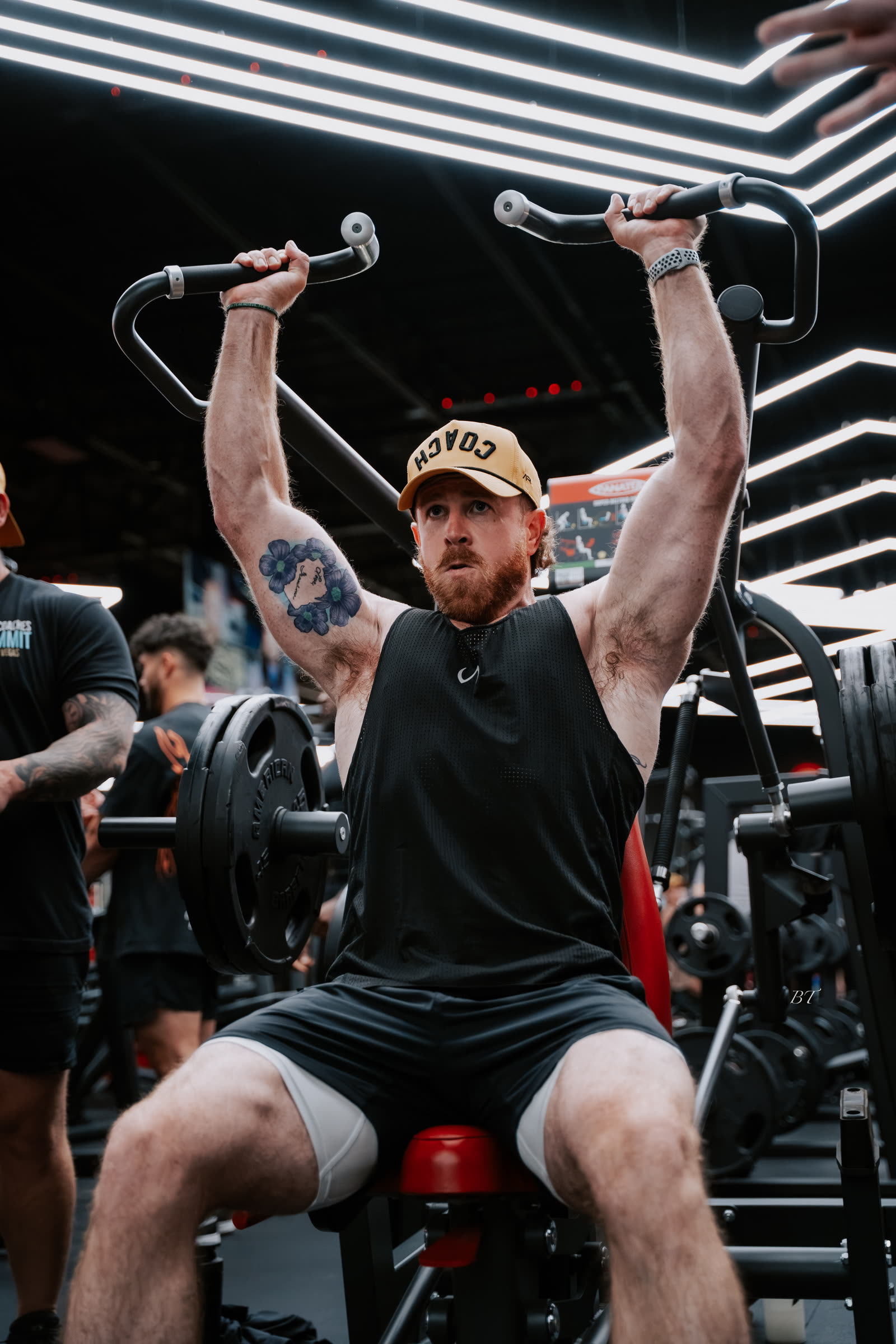 Dan Effinger pressing overhead under the gym neon