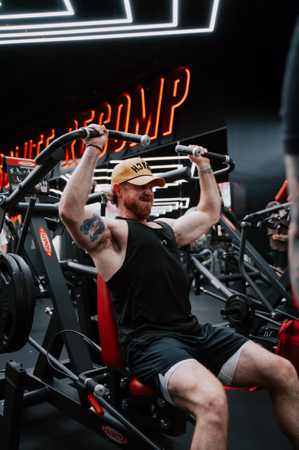 Dan Effinger in a COACH cap pressing overhead under the Recomp neon
