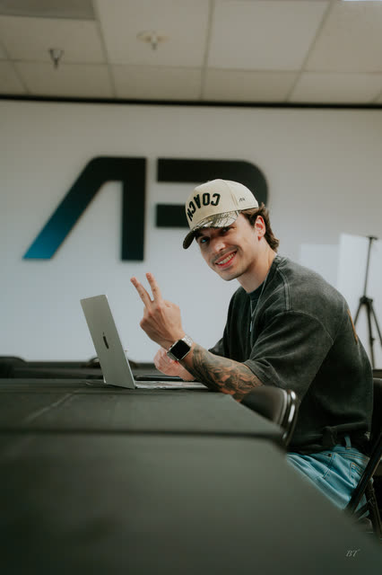 Attendee in a COACH cap throwing a peace sign at his laptop in the AR office