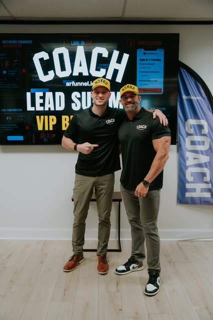 Bakker Shields and Mike Crowson posing arm in arm under the COACH Lead Summit VIP screen