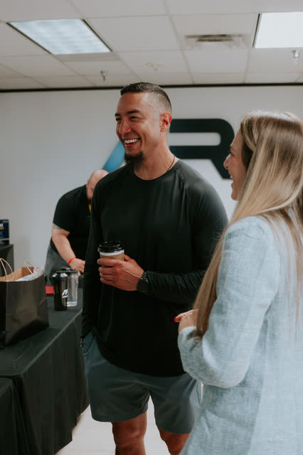 Attendee laughing with a coffee beside the AR logo wall