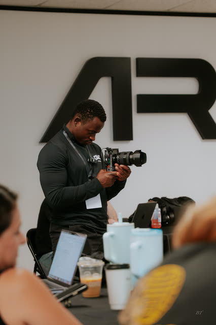 Event photographer checking a shot in front of the AR logo wall