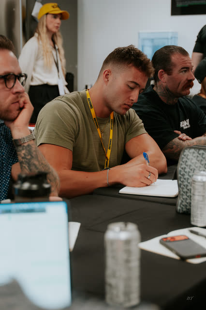 Attendee in an olive tee writing notes at the breakout table