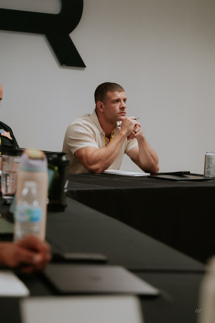 Attendee listening with hands clasped under the AR logo