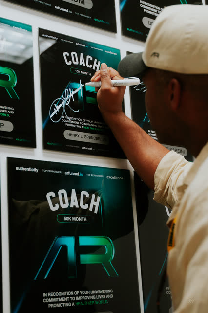 Coach signing his COACH award plaque on the wall of honor