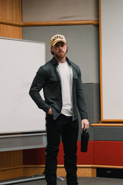 Dan Effinger in a COACH cap standing by the whiteboard before the session