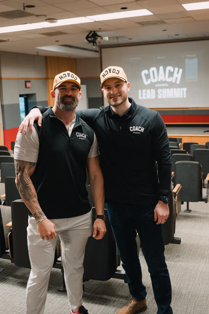Mike Crowson and Bakker Shields arm in arm under the COACH Lead Summit screen