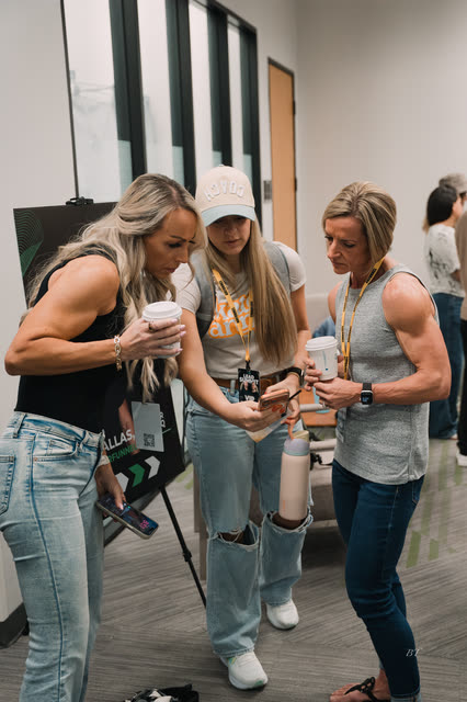 Coaches looking at a phone together by the Lead Summit poster