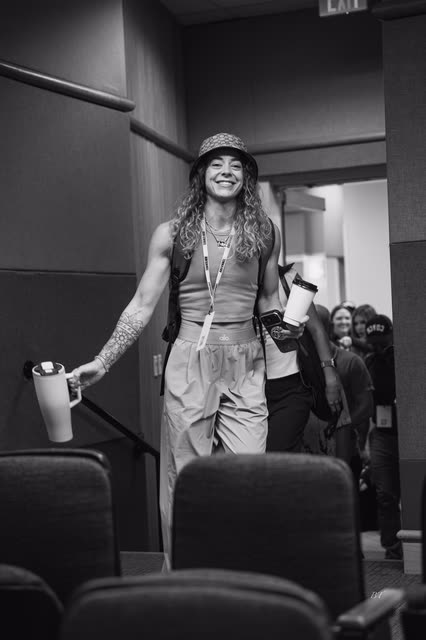 Black and white shot of a coach in a bucket hat smiling as she walks in