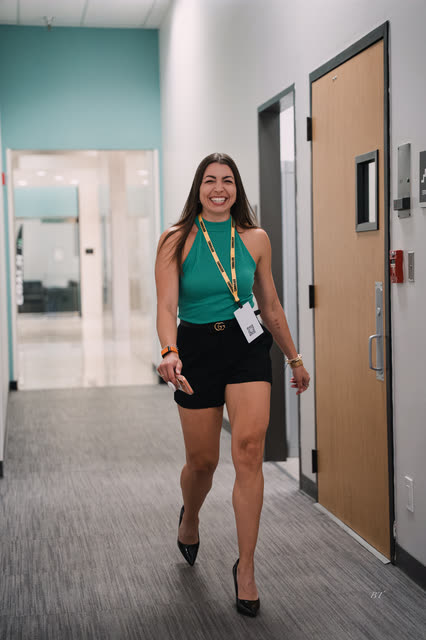 Coach in a teal top smiling as she walks down the hallway