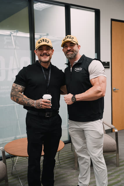 Coach in a yellow COACH cap posing with Mike Crowson